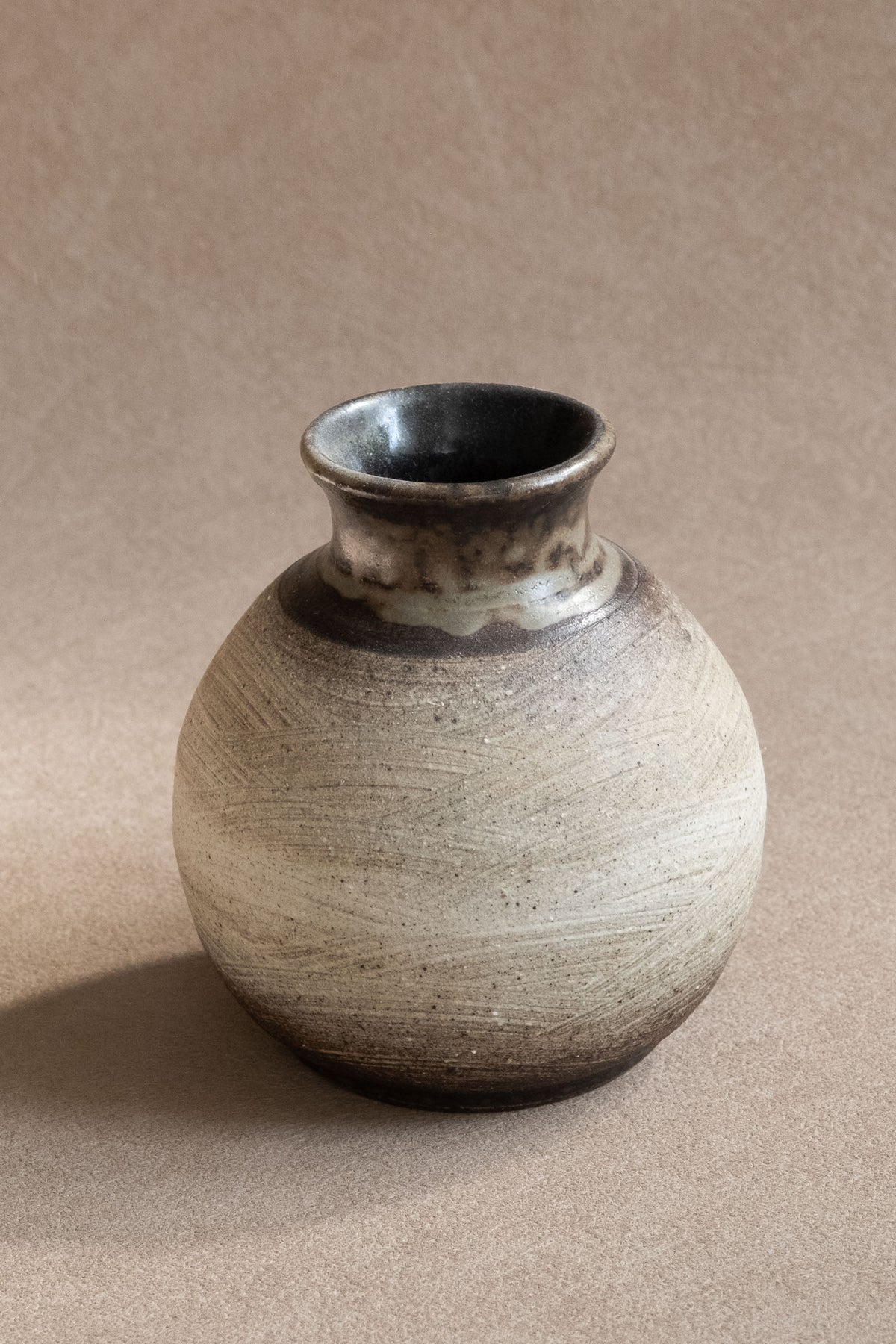 Angled view of the small Japanese vase showing its rounded profile and dark brown-black rim.
