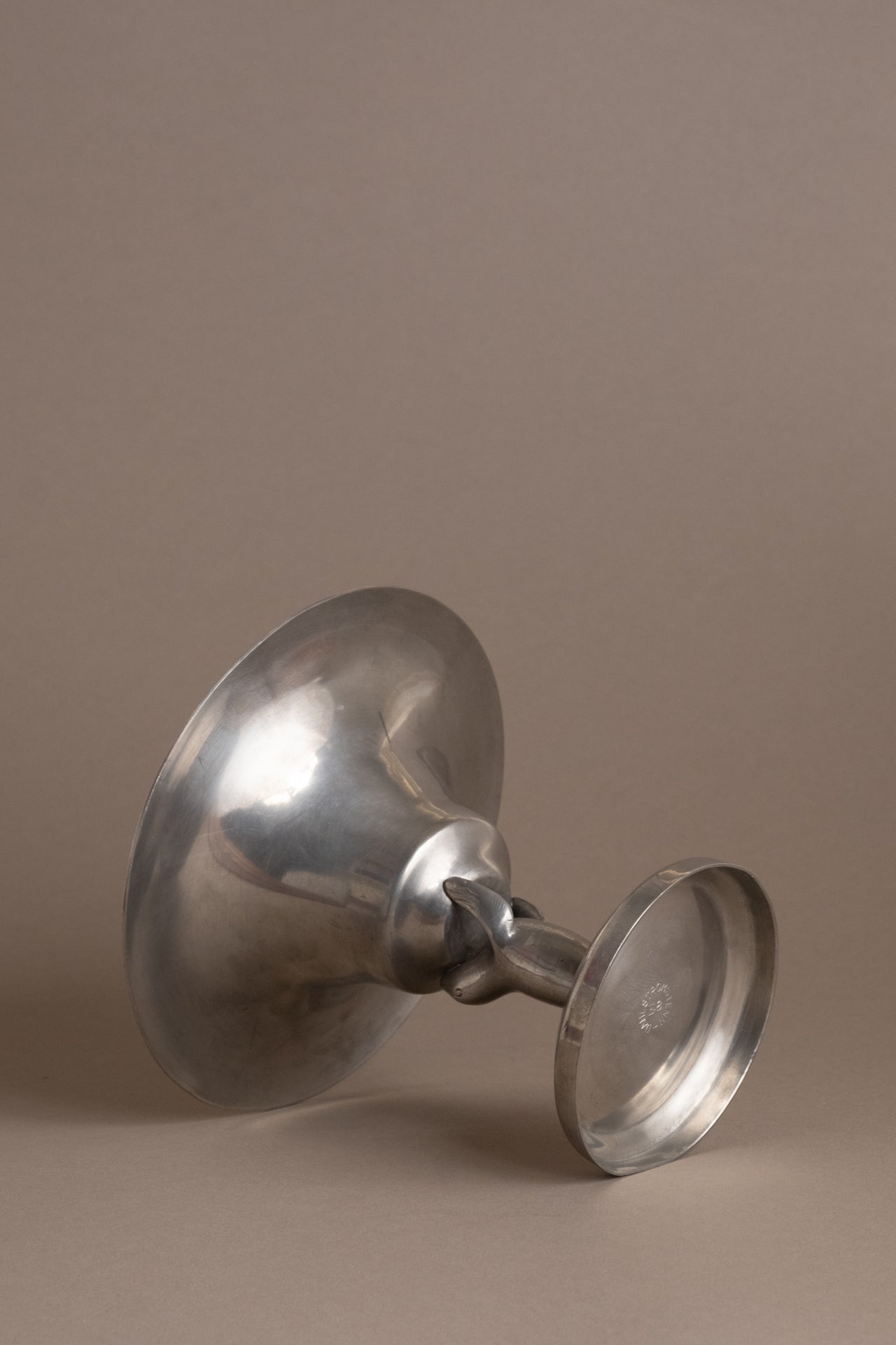 Dahlströms Tenn pewter sea lion pedestal bowl photographed on its side, showing pedestal and base.