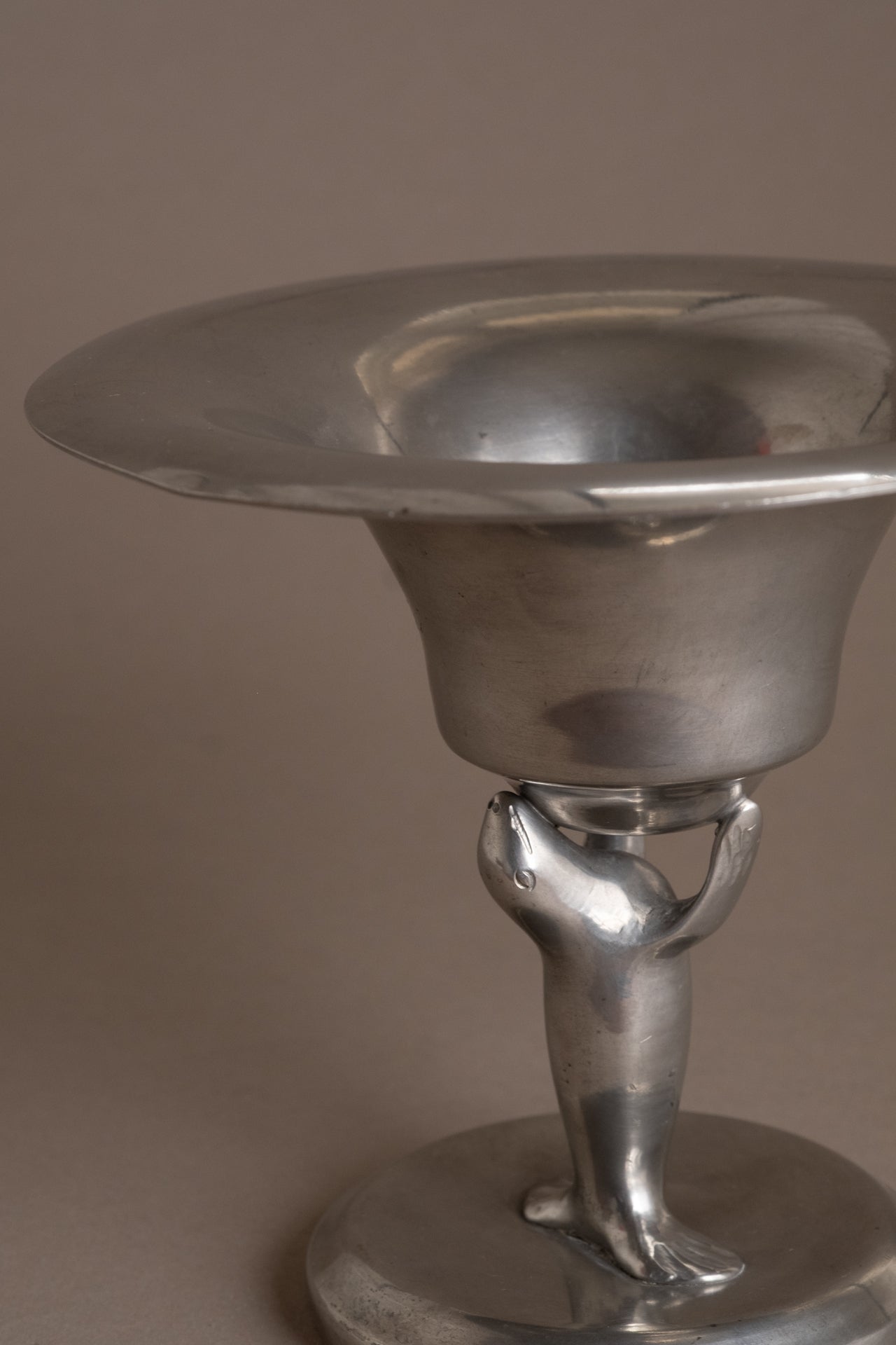 Detail of the stylised sea lion figure supporting the pewter bowl, Dahlströms Tenn, Sweden.