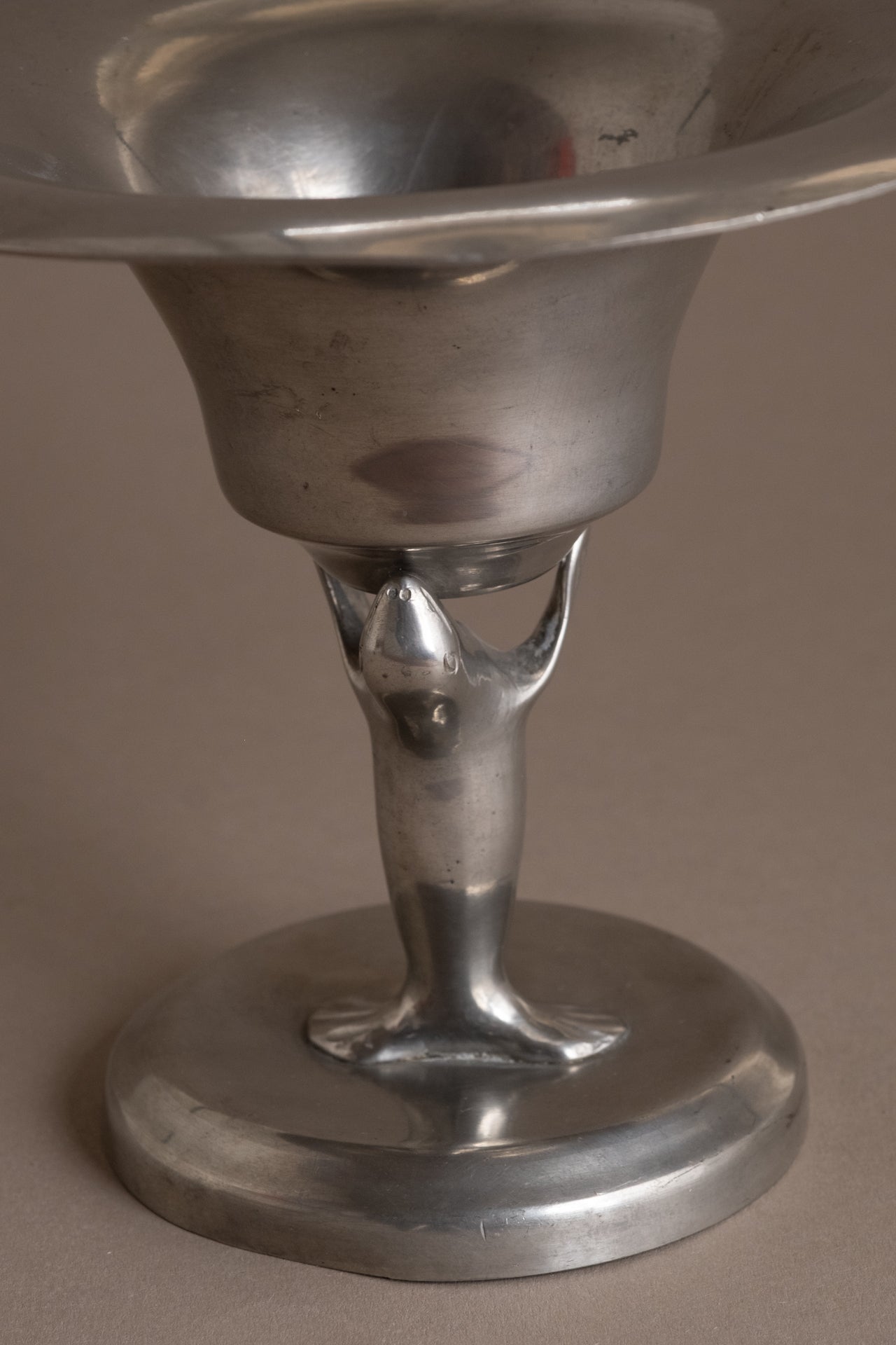Close-up of the pedestal base and sea lion support on the Dahlströms Tenn pewter bowl.