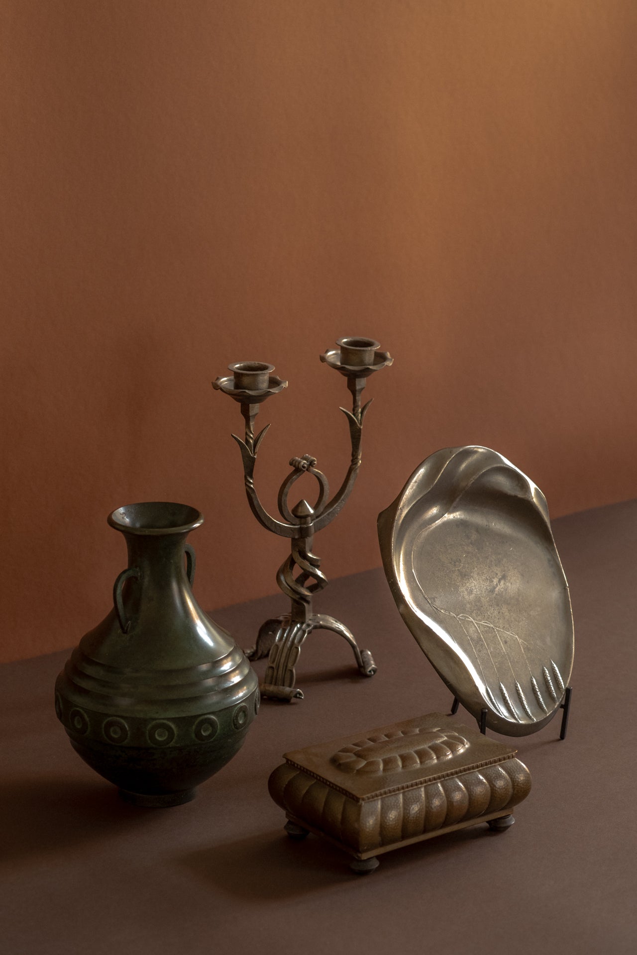 Antique and vintage metal design objects including Japanese patinated bronze vase, German wrought iron candleholder, WMF brass jewellery box and Kayserzinn pewter sculptural plate.