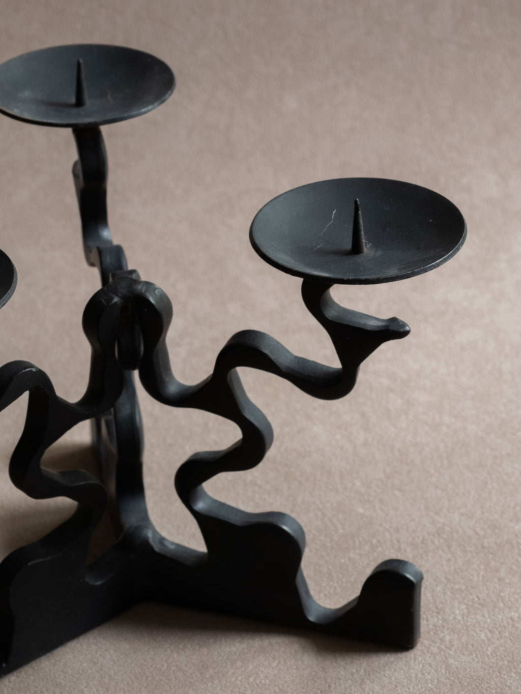 Detail view of the right candle dish and pricket spike, with visible light surface scratches and the curved forged iron arm below.