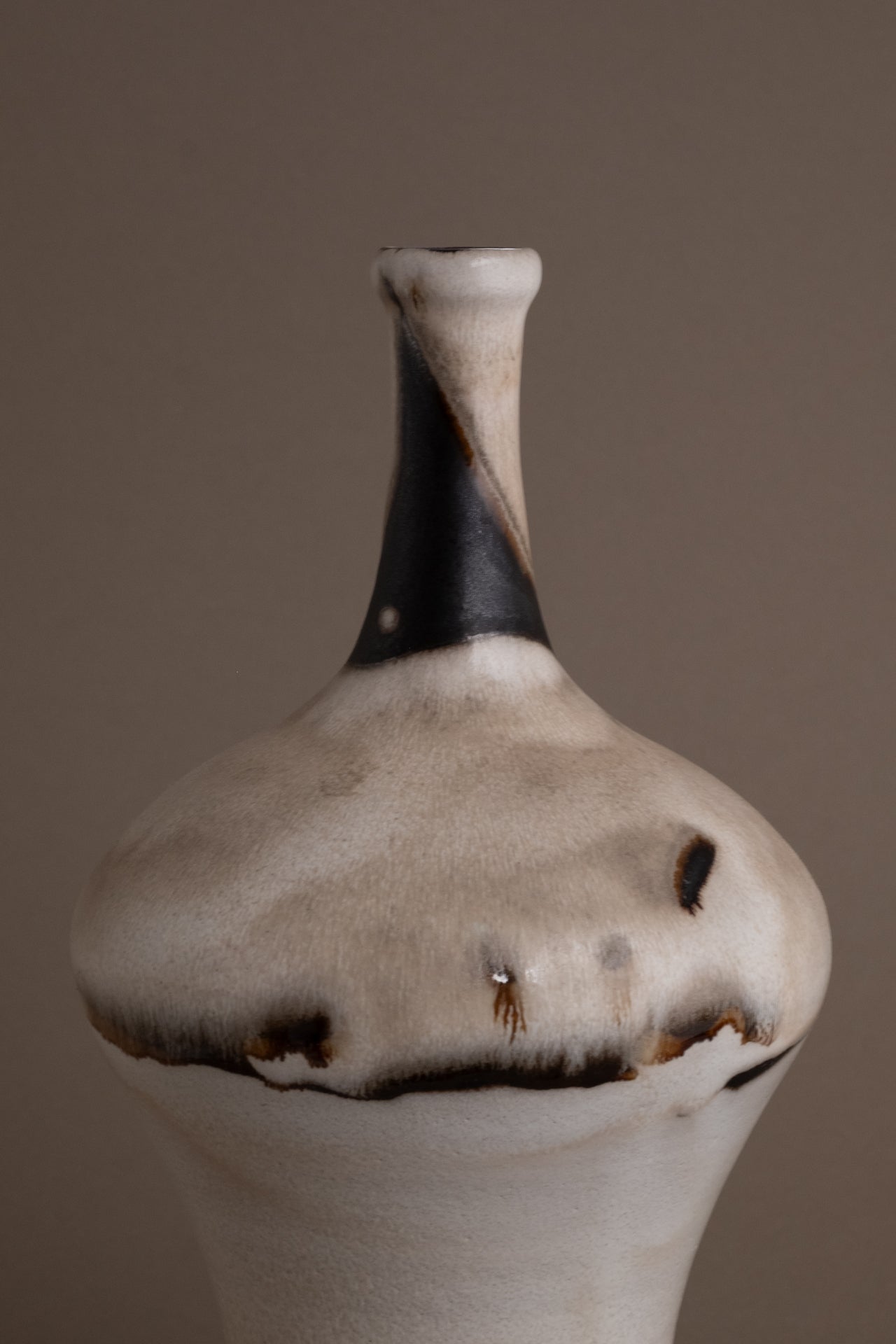 Close view of the Elly and Wilhelm Kuch studio ceramic vase showing the broad shoulder and black abstract glaze across the cream surface.