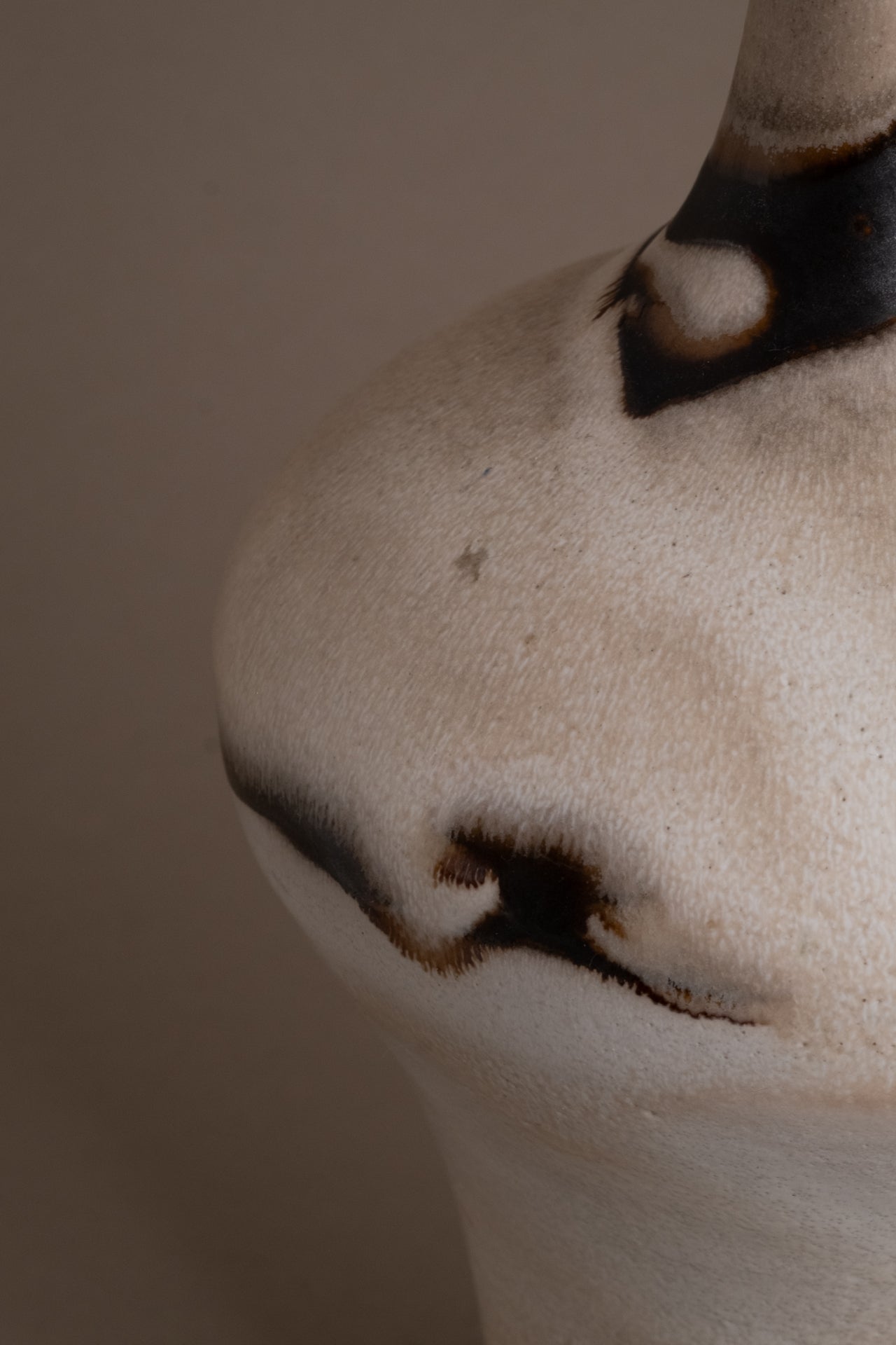 Detail of the cream and charcoal glaze on the Kuch studio ceramic vase, showing the irregular abstract painted edge.