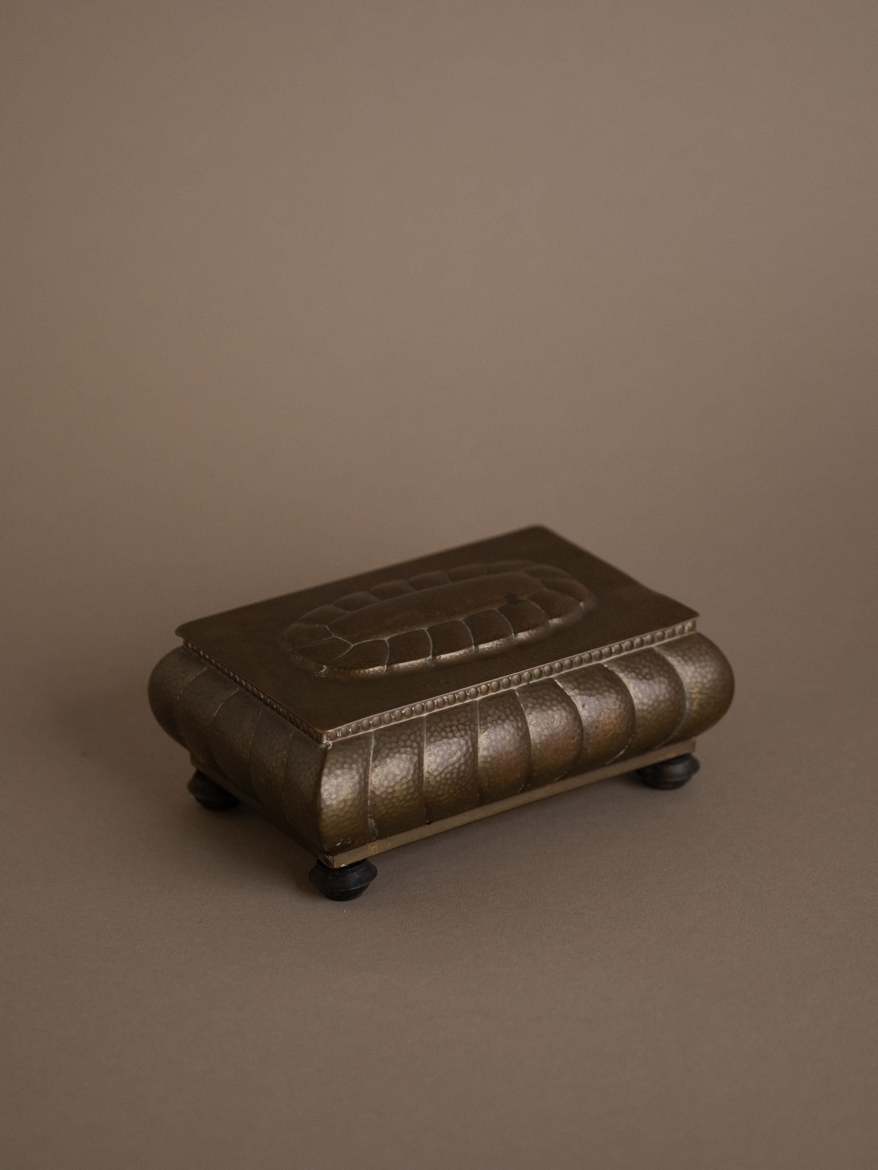 Front view of closed WMF hammered brass jewellery box on Bakelite feet, Germany, 1928–1935.