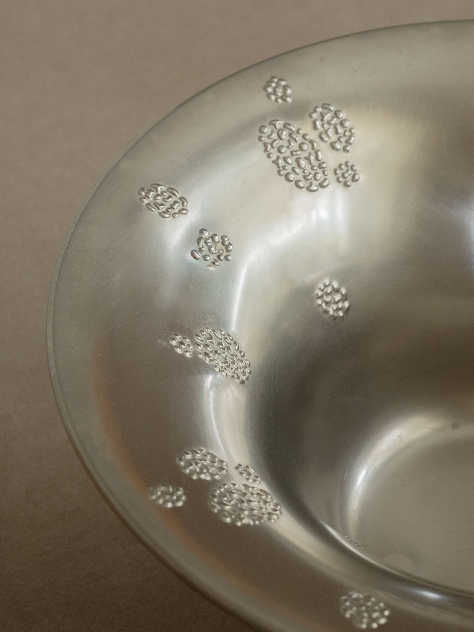 Interior close-up of a WMF metal pedestal tazza bowl showing raised dotted clusters on the silver-toned surface.
