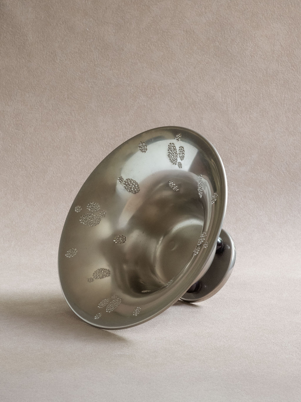 Angled view into a WMF metal pedestal tazza bowl showing the flared interior and raised dotted decoration.