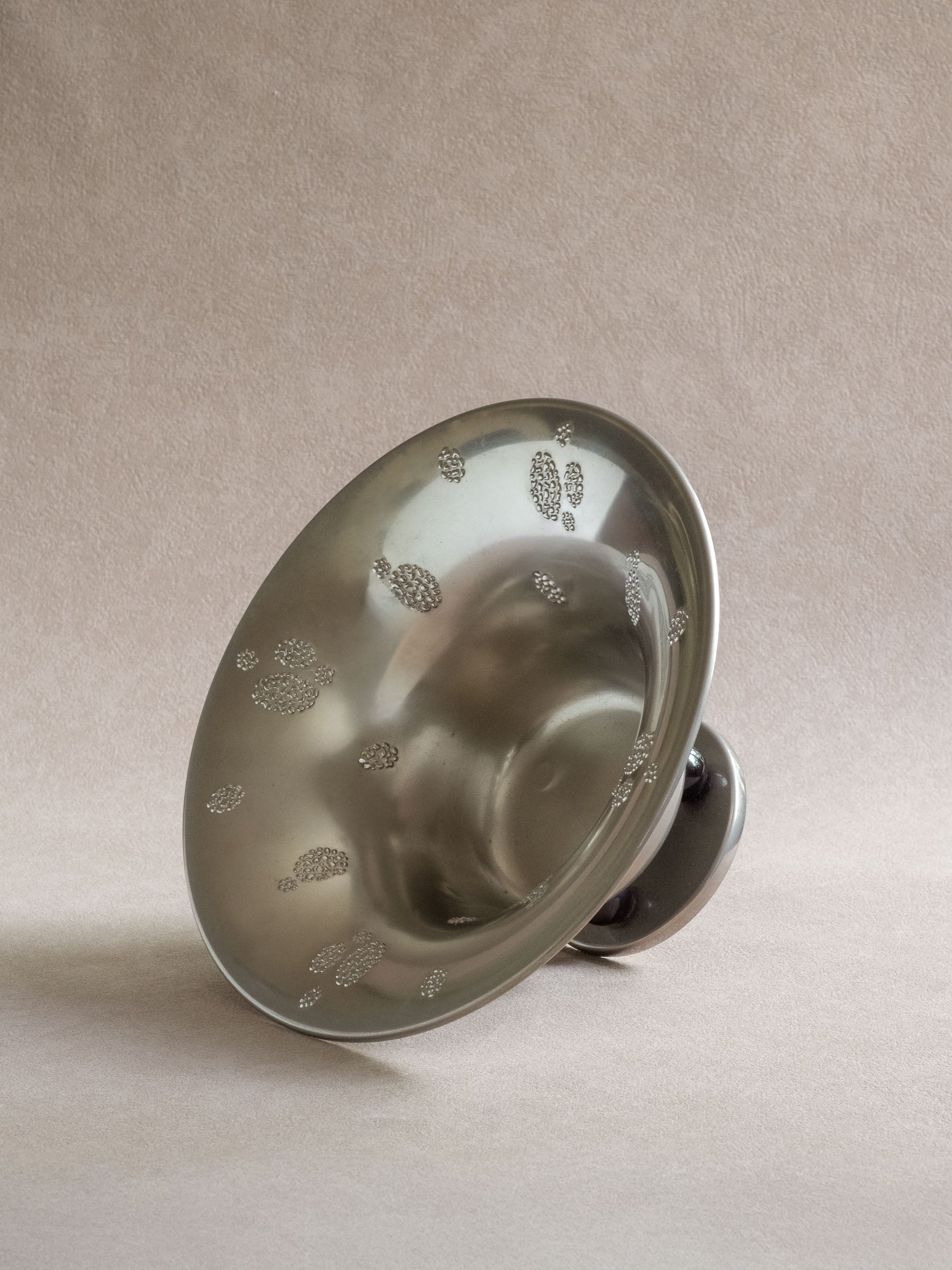 Angled view into a WMF metal pedestal tazza bowl showing the flared interior and raised dotted decoration.