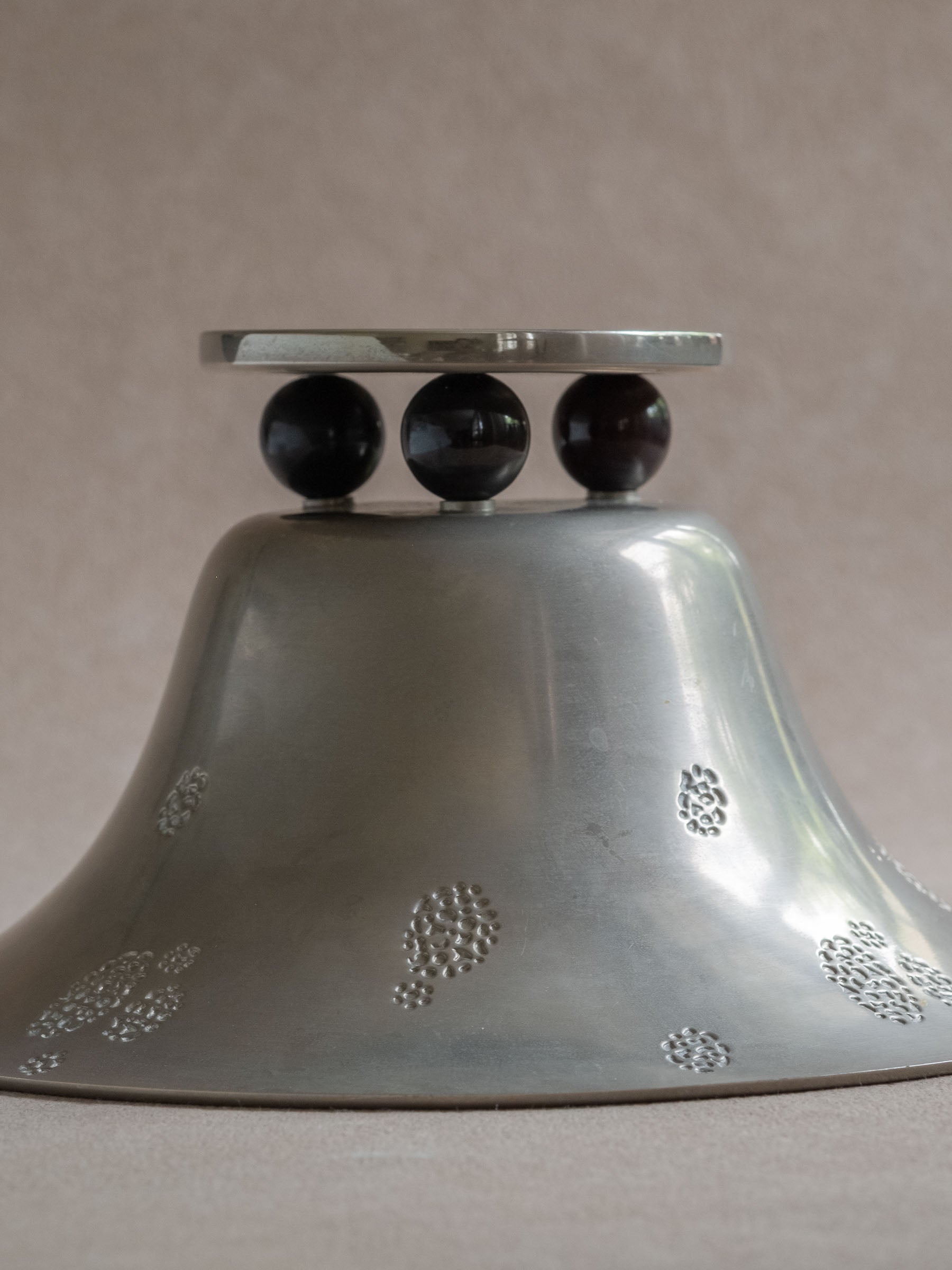 Underside view of a WMF metal pedestal tazza bowl showing the flared body, black ball feet, and raised dot decoration.