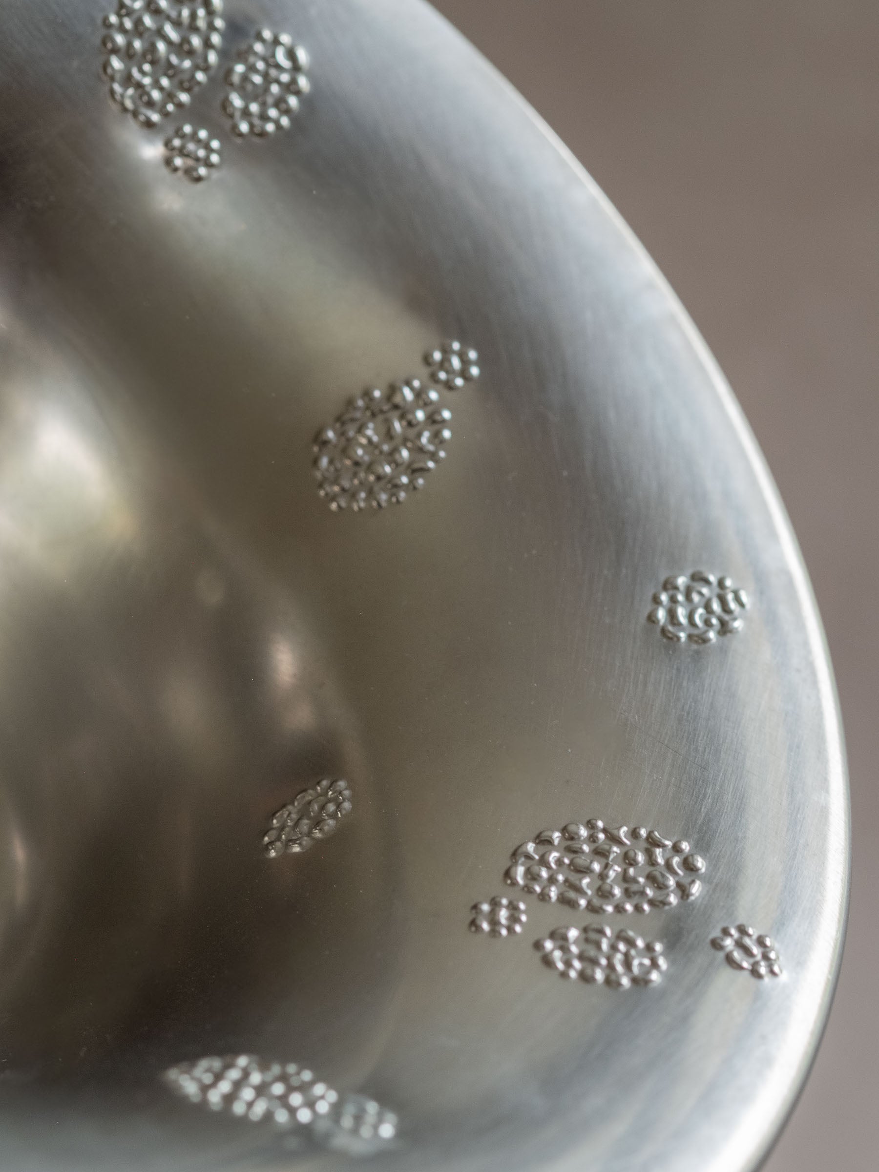 Close-up of the interior rim of a silver-toned WMF metal pedestal tazza bowl with raised dotted clusters.