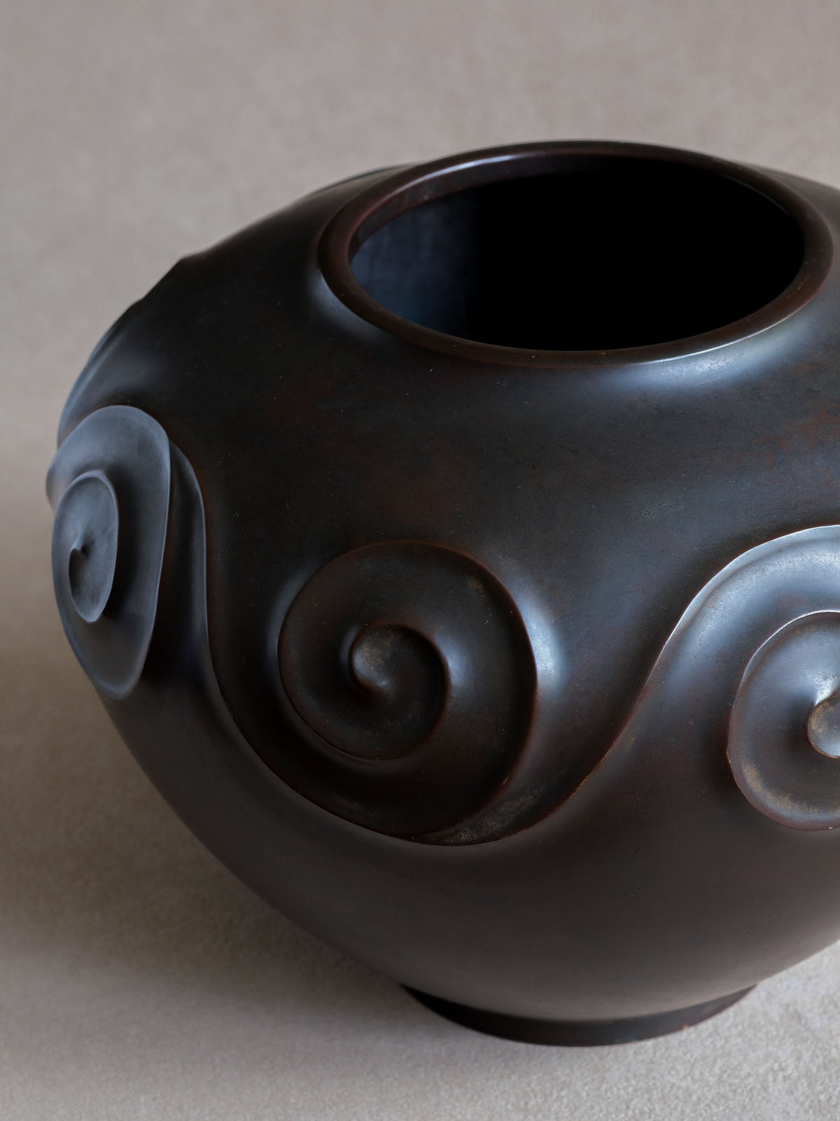 Close-up of raised spiral gurimon pattern wrapping around the rounded Yashima Boshū bronze vase.