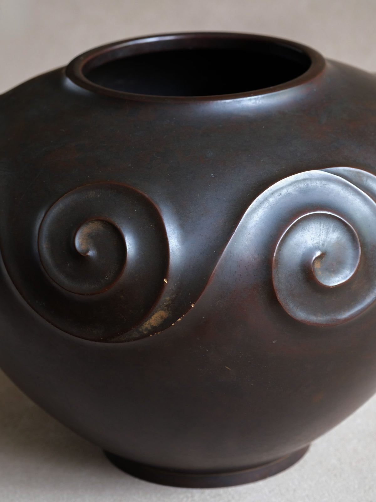 Three-quarter detail of Yashima Boshū vase showing layered spiral relief and minor surface wear.